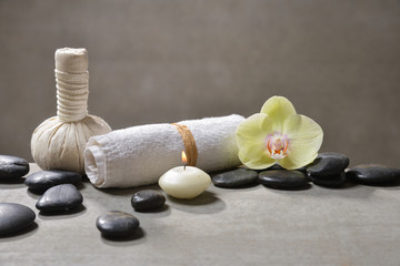 Fototapeta na wymiar candle with pile of black stones and white frangipani, herbal ball.towel on gray background