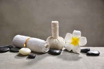 Fototapeta na wymiar candle with pile of black stones and white frangipani, herbal ball.towel on gray background