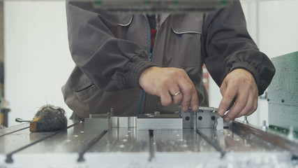 Worker with a scraper chamfering removing burrs on metal object for manufacturing industrial CNC...