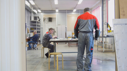 Fototapeta premium Male workers at manufacturing of CNC machines cleaning the workspace