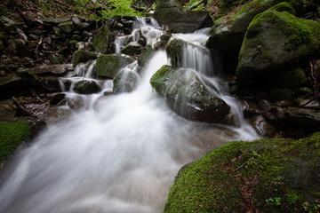 Beautiful mountain rainforest waterfall with fast flowing water and rocks, long exposure.