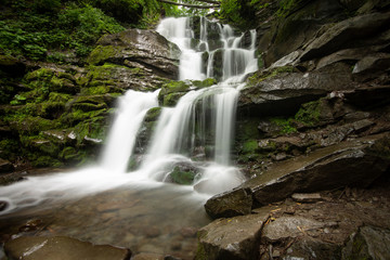 Fototapeta na wymiar Beautiful mountain rainforest waterfall with fast flowing water and rocks, long exposure.