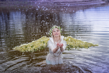 Nice blonde girl with white flower wings in a water