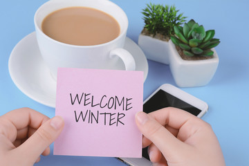 Woman hands holding note paper with "Welcome winter" text