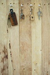 House key with wooden home keyring hanging on wood board background, property concept, copy space