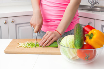 Young attractive woman cooking salad indoors at the kitchen