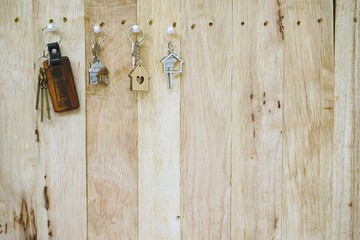 House key with wooden home keyring hanging on wood board background, property concept, copy space