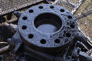 Oil well and small crude lake at the well head in Fang oil field, crude oil from oil well with reflex of pumpjack. blowout preventer device with flanges on the oil rig