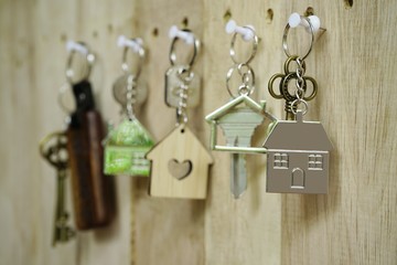 Fototapeta na wymiar House key with wooden home keyring hanging on wood board background, property concept, copy space