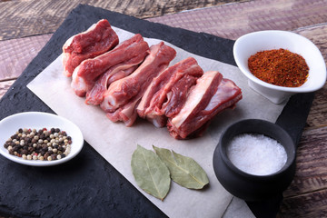 Raw fresh meat, uncooked lamb or beef ribs with pepper, garlic, salt and spices on dark stone background, Ready for cooking. copy space.