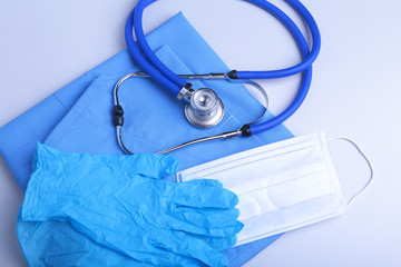 Medical stethoscope head lying on blue doctor uniform closeup. Medical tools and instruments shop,...