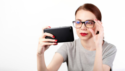 Portrait of a young attractive woman making selfie photo on smartphone isolated on a white background