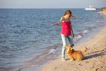 girl playing with a dog on the beach