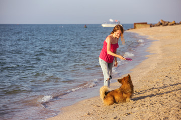 girl playing with a dog on the beach