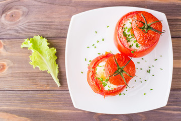 Fresh tomatoes baked with cheese and chicken egg on a plate and salad on a wooden table. Top view.