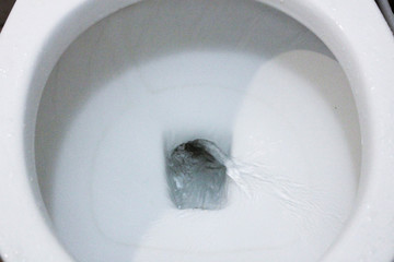 selective focus close up flushing toilet bowl for sanitary, Toilet, Flushing Water, close up, water flushing in toilet, A photo of a white ceramic toilet bowl in the process of washing it off. Ceramic