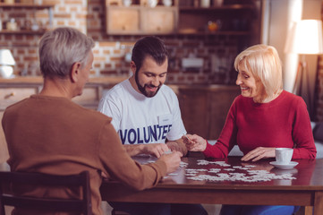 Fototapeta premium One team. Delighted mature woman keeping smile on her face while making picture with puzzles