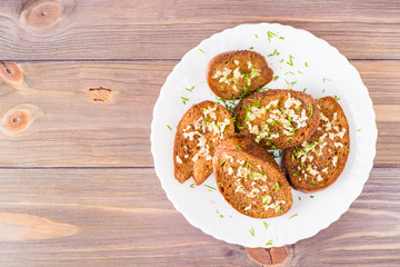 Fresh rye garlic croutons with dill on a plate on a wooden table. Top view. Copy space