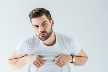 Obraz premium Stylish young man in white shirt sitting on chair isolated on white background