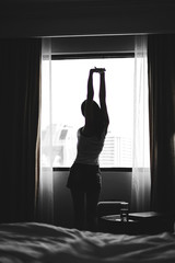 Asia woman  get up on the morning and standing near the window.lady fresh and ready to go to work.silhouette and dark style.  