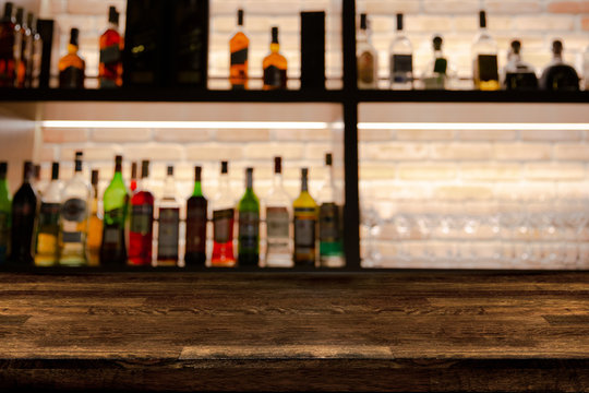 Empty dark wooden bar counter with blur background bottles of restaurant.