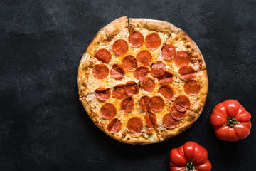 Pepperoni pizza on black concrete background. American pepperoni pizza, top view