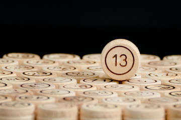 Unlucky number 13 on the wooden barrels lotto. Black background. Close up