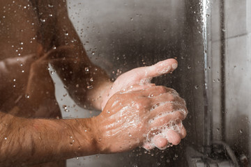 Cropped view of man washing hands with foam in shower - Powered by Adobe