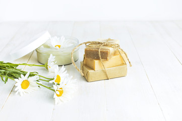 Natural cosmetics, handmade soaps, face and body cream with chamomile flower on a light background. Spa concept organic cosmetic. Natural beauty product.