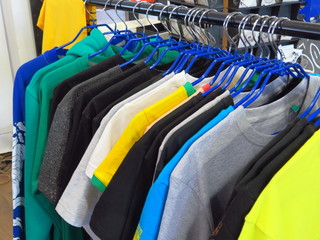 Obraz premium Clothes hanging on a hanger in the store. Choice of Women's t-shirts of different colors on metal hangers.