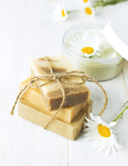 Natural cosmetics, handmade soaps, face and body cream with chamomile flower on a light background. Spa concept organic cosmetic. Natural beauty product.
