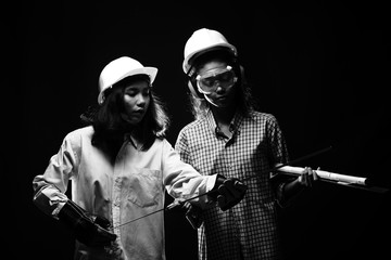 Two Beautiful Asian Architect Engineer women in hard hat, protector glasses goggle mask ear muff