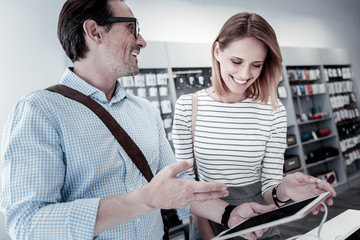 Shopping together. Pleasant young friendly couple coming to a new electronics shop together