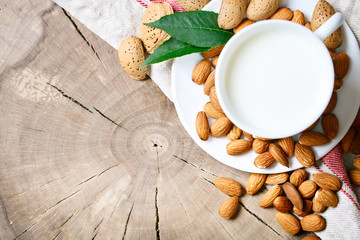 Almond and almond milk on a wooden table in the summer garden. Useful food.