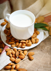 Almond and almond milk on a wooden table in the summer garden. Useful food.