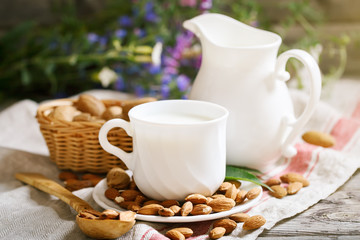 Almond and almond milk on a wooden table in the summer garden. Useful food.