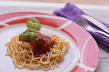 Delicious homemade spaghetti whit tomato sauce-salsa-served at plate at light wooden background/ top view