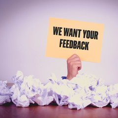 HAND HOLDING YELLOW PAPER WITH WE WANT YOUR FEEDBACKCONCEPT