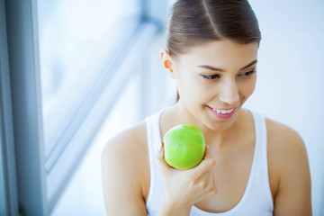 Health and Beauty. Beautiful Young Girl With White Teeth Holding Hands Of Fresh Green Apple. A Woman With A Beautiful Smile. Tooth Health