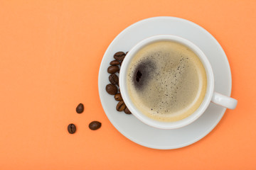 Cup of coffee and coffee beans on peach background