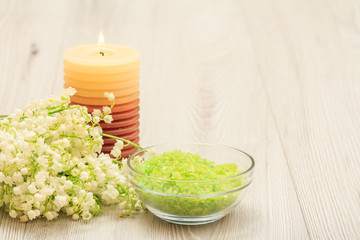Bouquet of lilies of the valley, burning candle and bowl with sea salt