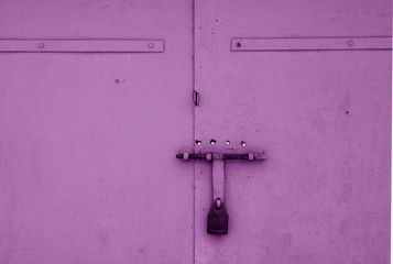 Old padlock on metal gate in purple color.