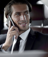 businessman in his car with a laptop talking on the phone