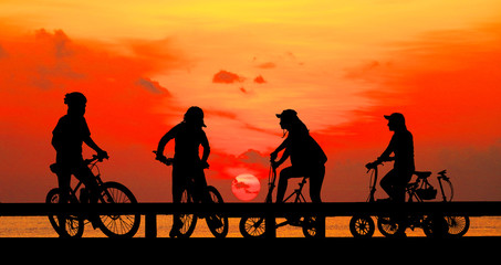 Fototapeta na wymiar Silhouette group friend and bike relaxing on blurry sky background.