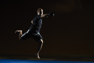 Athlete jumping over blue tatami beats with a hand