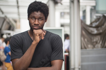 Naklejka premium Thoughtful African man thinking; portrait of pensive young adult african man thinking about plan, idea, future, brain storming concept; west African young adult man model