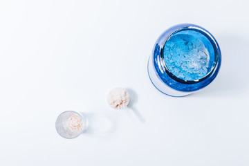 Opened jar of protein powder sport supplements near a full scoop