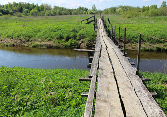 Fototapeta premium Old wooden bridge over river in summer countryside