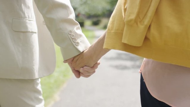 Hands of a senior couple walking together in love, in slow motion