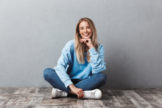 Happy young blonde girl sitting on a floor
